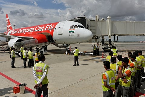 Ground crew look on as an AirAsia India Airbus A320 prepares to embark on its inaugural domestic flight to Goa from the Kempe Gowda International Airport (KGIA) in Bangalore on June 12, 2014. | File AFP