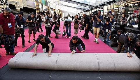 Workmen are trailed by photographers as they roll out the red carpet for the Oscars in front of the Dolby Theatre on Wednesday, Feb. 24, 2016, in Los Angeles. The 88th Academy Awards will be held on Sunday. | AP