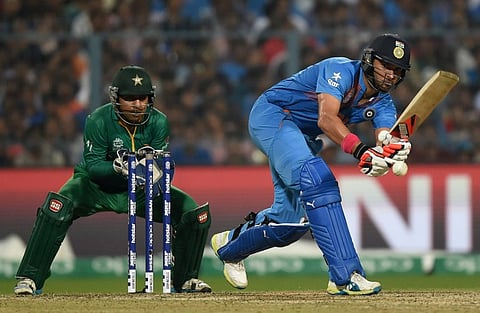 India's Yuvraj Singh plays a shot as Pakistan's Sarfaraz Ahmed looks on during the World T20 cricket tournament match between India and Pakistan at the Eden Gardens cricket stadium in Kolkata on March 19, 2016. | AFP