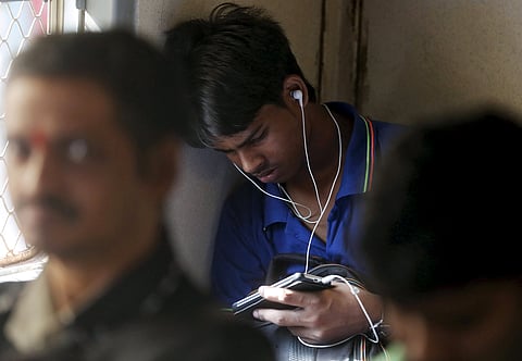 A man watches a video on his mobile phone as he commutes by a suburban train in Mumbai, India, March 31, 2016. REUTERS