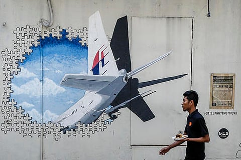 In this Tuesday, Feb. 23, 2016, file photo, a waiter walks past a mural of flight MH370 in Shah Alam outside Kuala Lumpur, Malaysia.