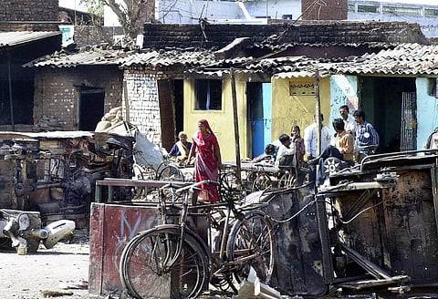 A Hindu family returns to what remains of their burnt home along the highway at Naroda Paldi, as troops bring a tense calm 02 March 2002, after three days of riots in Ahmedabad. (File Photo | AFP)