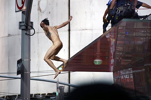 A naked man jumps off the rear staircase ledge above the TKTS Broadway ticket booth in New York's Times Square, Thursday, June 30, 2016. Police said the man, who was shouting about presumptive Republican presidential nominee Donald Trump, was conscious a