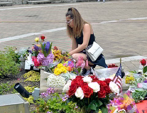 Vanessa Buzgheia, of Louisville, Ky., sets up flowers that were knocked over by the wind at a memorial to Muhammad Ali at the Muhammad Ali Center. |AP