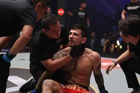 Doctor Warren Wang, ONE Championship's Vice President of Medical Services, examines an athlete after a knockout loss. | Reuters