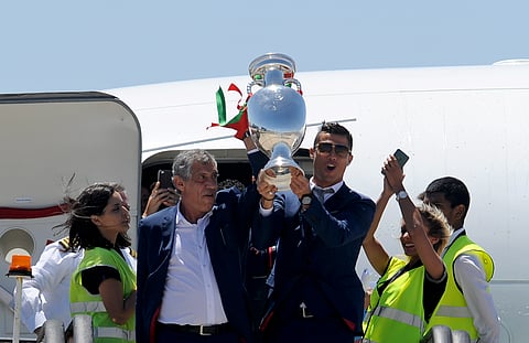 Portugal's Cristiano Ronaldo and coach Fernando Santos, left, lift the Euro 2016 trophy after defeating France in the final, as they arrive at the Humberto Delgado Airport in Lisbon, Portugal, Monday, July 11, 2016. | AP