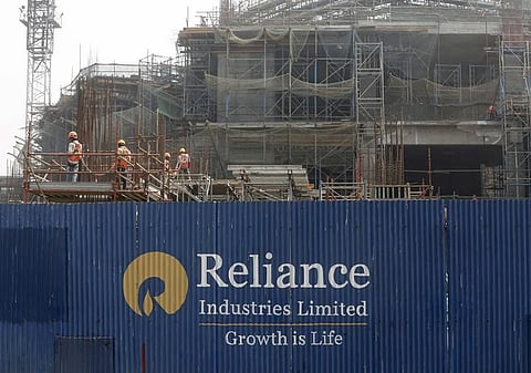 Labourers work behind an advertisement of Reliance Industries Limited at a construction site in Mumbai | Reuters
