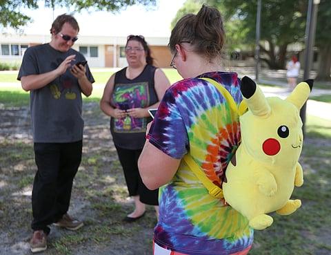 Victoria Baker, right, turns to check her phone as she plays "Pokemon Go" with her friends Trey Cosson, left, and Kayleigh Cosson as Gulf Coast State College hosted a "Pokemon Go" event on the college campus in Panama City, Fla. (AP)