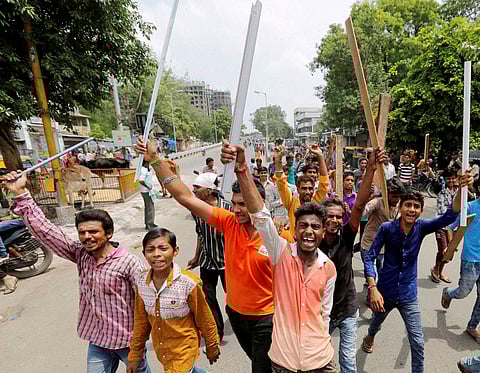 Dalit community member hold wooden sticks and shout slogans during a protest | PTI