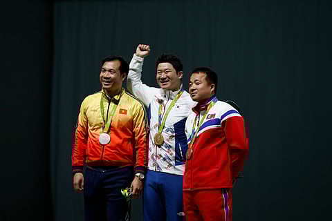 Gold medalist Jin Jong-oh, center, of South Korea is flanked by silver medalist Hoang Xuan Vinh, left, of Vietnam and bronze medalist Kim Song Guk of North Korea, during the award ceremony for the men's 50 meter pistol event at Olympic Shooting Center at