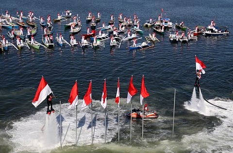 Fishermen look on as flyboarders raise Indonesian flags at Losari beach in Makassar, South Sulawesi province, on August 17, 2016, during the countries 71st independent day anniversary. (AFP)
