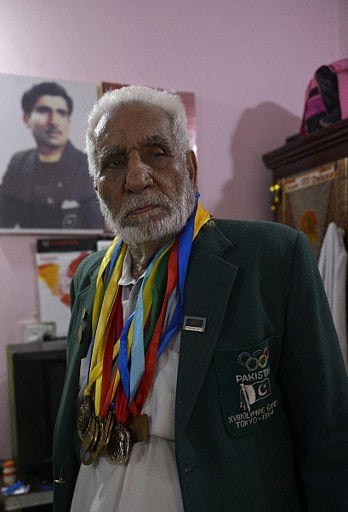 In this photo taken on June 23, 2016, former Pakistani Olympian Muhammad Ashiq wears his medals as he poses at his residence in Lahore. | AFP