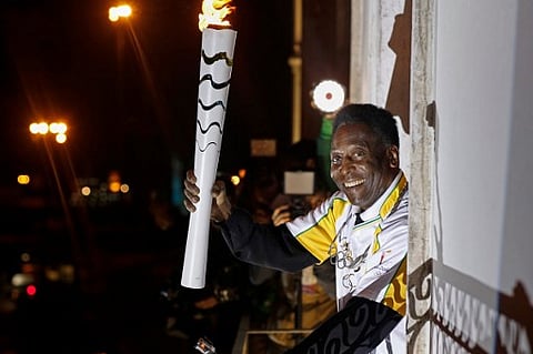 Handout picture released by the Rio 2016 Olympic Committee showing former football player Pele holding the Olympic flame at the Pele Museum in Santos, Sao Paulo State, Brazil. (File Photo | AFP)