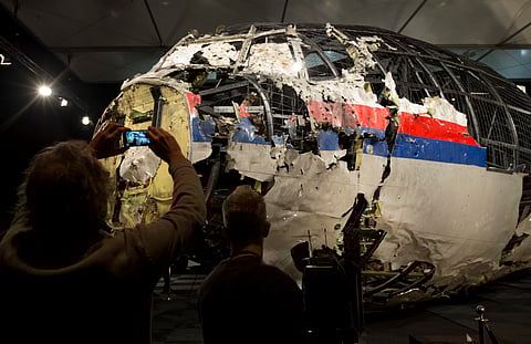 In this Tuesday, Oct. 13, 2015 file photo, journalists take images of part of the reconstructed forward section of the fuselage after the presentation of the Dutch Safety Board's final report into what caused Malaysia Airlines Flight 17 to break up high 