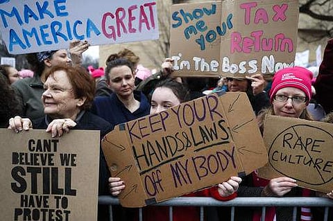Lily Donahue of Wappingers Falls, N.Y., center, holds a sign along the barricades at the Women's March on Washington during the first full day of Donald Trump's presidency, on January 21. (Photo | AP)