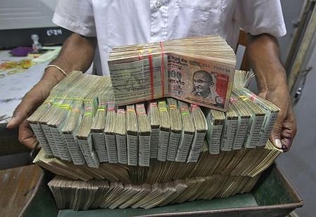 An employee poses with the bundles of Indian rupee notes inside a bank in Agartala. (File Photo | Reuters)
