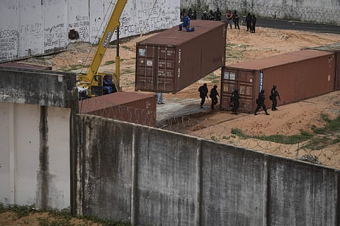 Military Police officers cross under a temporary wall made from a shipping containers separation as they enter the Alcacuz prison in Nisia Floresta, near Natal, Brazil, Tuesday, Jan. 24, 2017. | AP