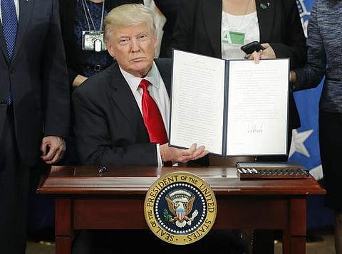 President Donald Trump holds up an executive order for border security and immigration enforcement improvements after signing the order during a visit to the Homeland Security Department headquarters in Washington, Wednesday, Jan. 25, 2017.| AP