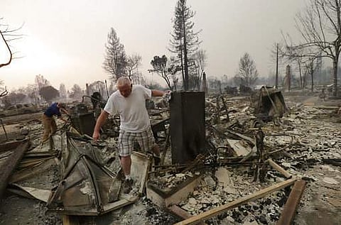 A family look through the remains of their home destroyed by fires in Santa Rosa in California. (Photo| AP)