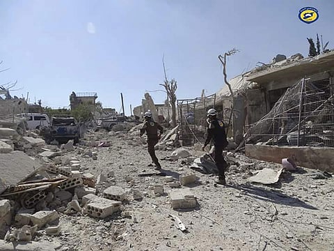 Defence workers run through the damaged buildings after airstrikes in the village of Hass in the Idlib province. (File photo | AP)