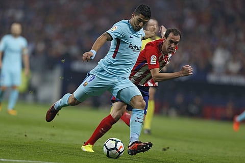 Barcelona's Luis Suarez, front, shoots the ball next to Atletico Madrid's Diego Godin during a Spanish La Liga soccer match. | AP