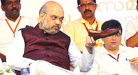 BJP national president Amit Shah checking his shoe after completing the march as part of BJP’s Jana Raksha Yatra which concluded at Putharikandam Maidan in Thiruvananthapuram on Tuesday | Kaviyoor Santhosh