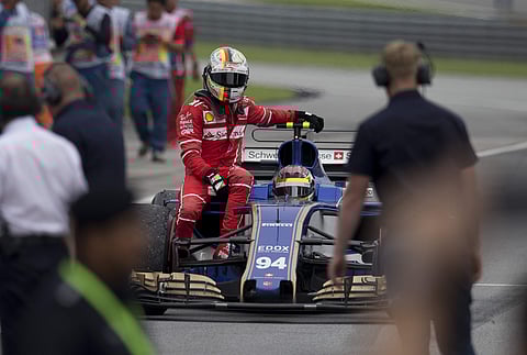 Ferrari driver Sebastian Vettel of Germany returns to the pit area with a ride from Sauber driver Pascal Wehrlein of Germany after the Malaysian Formula One Grand Prix in Sepang, Malaysia, Sunday, Oct. 1, 2017. | AP