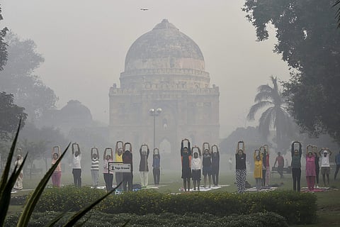 People performing yoga at Lodhi Garden as smog covers it in New Delhi on Friday morning, a day after Diwali.  (PTI)