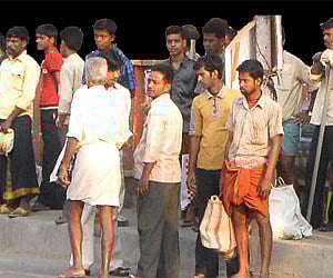 Migrant labourers wait for their contractors at the  Perumbavoor Junction. (EPS |P K Jeevan Jose)