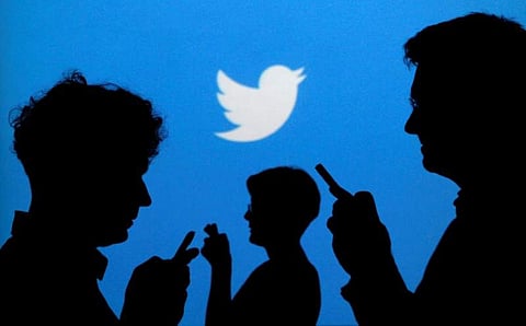 People holding mobile phones are silhouetted against a backdrop projected with the Twitter logo in this illustration picture. (File Photo | Reuters)