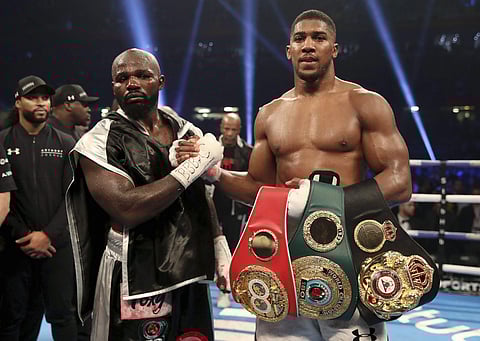 Anthony Joshua, right, celebrates victory over Carlos Takam, left, after the IBF World Heavyweight Title, IBO World Heavyweight Title and WBA Super World Heavyweight Title bout at the Principality Stadium, Cardiff, Wales, Saturday, Oct. 28, 2017. | AP
