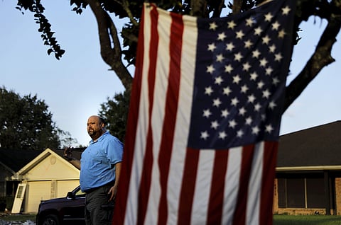 Wilton Johnson stands in Beaumont, Texas, Monday, Sept. 25, 2017, outside the gutted home he shares with his parents that was damaged by Hurricane Harvey. 'What good is a great environment if we're poor and living like cavemen? And vice versa, I understan