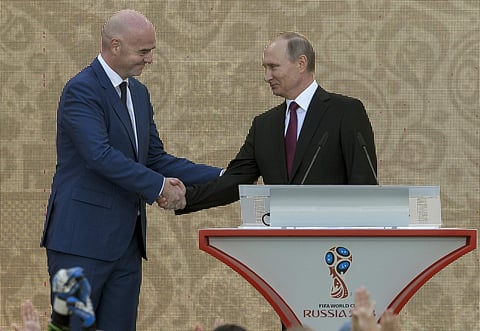 Russian President Vladimir Putin, right, and FIFA President Gianni Infantino shake hands as they present the FIFA World Cup trophy at Moscow's Luzhniki Stadium, Russia, on Saturday, Sept. 9, 2017. | AP