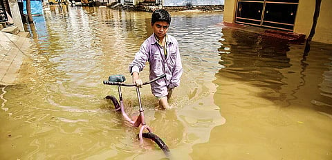 A boy wades through water with his bicycle at Raghavendra Nagar in Nacharam on Tuesday after the recent deluge in the city | Vinay Madapu
