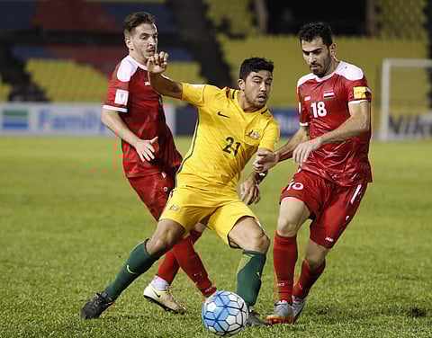 Australia's Massimo Luongo, center, fight for control of the ball with Syria's Mhd Zahed Almedani, right, during the 2018 World Cup qualifying football match between Syria and Australia at the Hang Jebat Stadium in Melaka. | AP