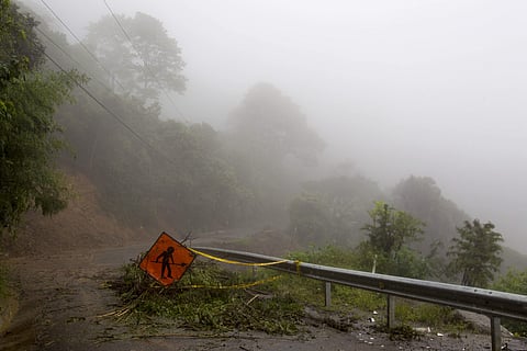 A men at work sign stands on a washed out road in Alajuelita on the outskirts of San Jose in Costa Rica. (Photo | AP)