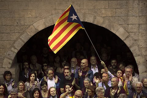 Catalan independence supporters, one waving an 'estelada', or Catalonia independence flag, applaud during a rally outside the city hall of Girona, Spain, Monday, Oct. 2, 2017. | AP