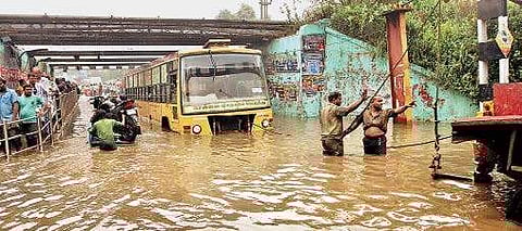 MTC staff struggling to pull a bus out of the flooded Ganesapuram subway. (EPS)
