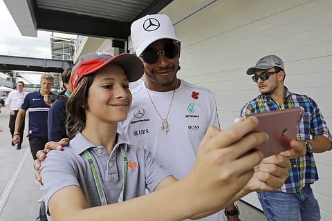 Mercedes driver Lewis Hamilton of Britain poses for a selfie with a fan in the paddock area after the second free practice at the Interlagos race track in Sao Paulo Brazil Friday Nov. 10 2017. | AP
