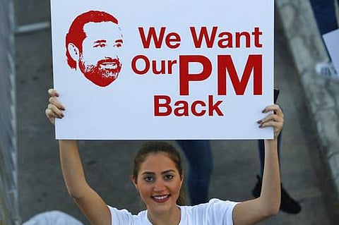 A Lebanese woman holds a placard supporting the outgoing Lebanese Prime Minister Saad Hariri to return from Saudi Arabia during the Beirut Marathon, in Beirut, Lebanon.|AP