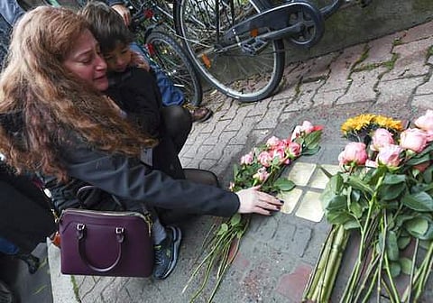 Mandy Eisemann from Dickerson, Maryland. with her son Levi (4), relatives of the Cohn family, places flowers at four 'Stolpersteine' (stumbling blocks) for Karolina Cohn and her family in Frankfurt, Germany.|AP