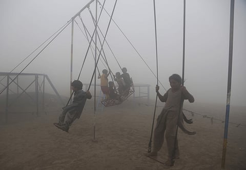 Children ride swings in a playground surrounded by smog in Lahore, Pakistan, Saturday, Nov. 11, 2017.  (Associated Press)