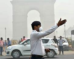 A traffic policeman wearing mask controls traffic amid smog in New Delhi. (File | PTI)