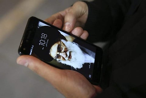 In this representational image, a Tehran resident works on his cell phone, with a portrait of Iranian Supreme Leader Ayatollah Ali Khamenei. (Photo | Associated Press)
