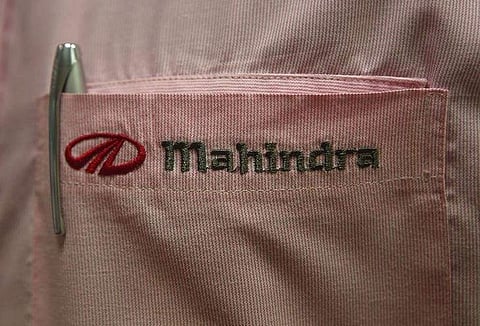 The logo of Mahindra & Mahindra Ltd is pictured on the pocket of a salesman's shirt as he poses inside the company's showroom in Mumbai. (File Photo | Reuters)