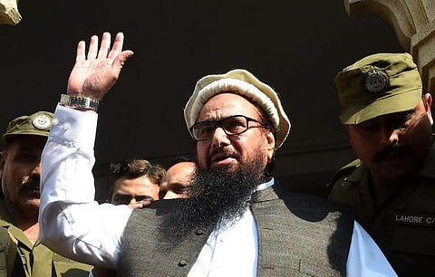 Pakistan head of the Jamaat-ud-Dawa (JuD) organisation Hafiz Saeed waves to supporters as he leaves a court in Lahore. | AFP