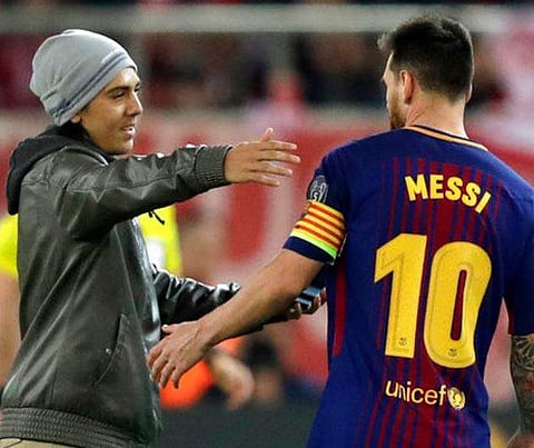 A fan who ran onto the pitch hugs Barcelona's Lionel Messi prior to taking a selfie with the player during the Champions League group D soccer match between Olympiakos and Barcelona at Georgios Karaiskakis stadium at Piraeus port, near Athens, Tuesday, Oc