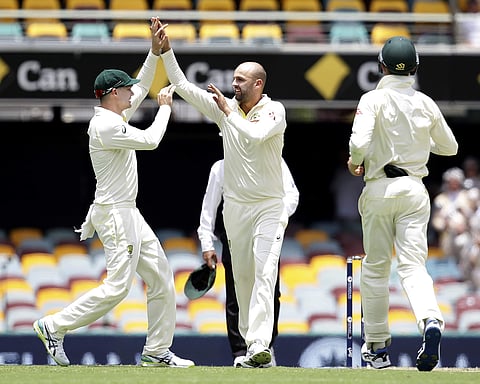 Australia's Nathan Lyon, right, celebrates with Peter Handscomb, left, after getting the wicket of England's Chris Woakes. | AP