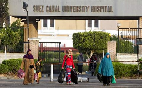 People walk outside the Suez Canal University hospital where injured worshippers an attack on a mosque receive treatment.|AP