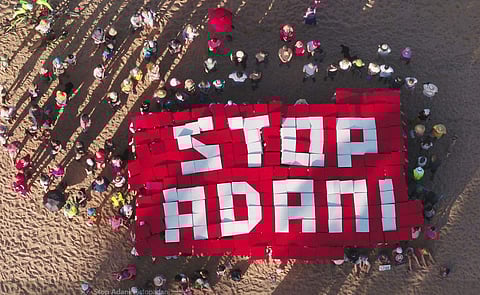 Protesters spelled out '#STOP ADANI' by standing in formation on the sand. (Twitter | Stop Adani)